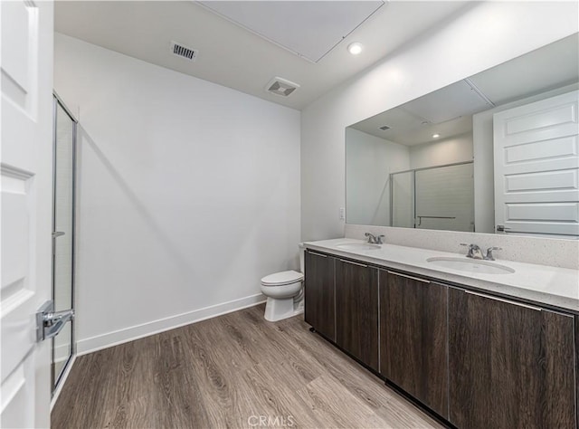 full bath featuring visible vents, wood finished floors, a shower with shower door, and a sink