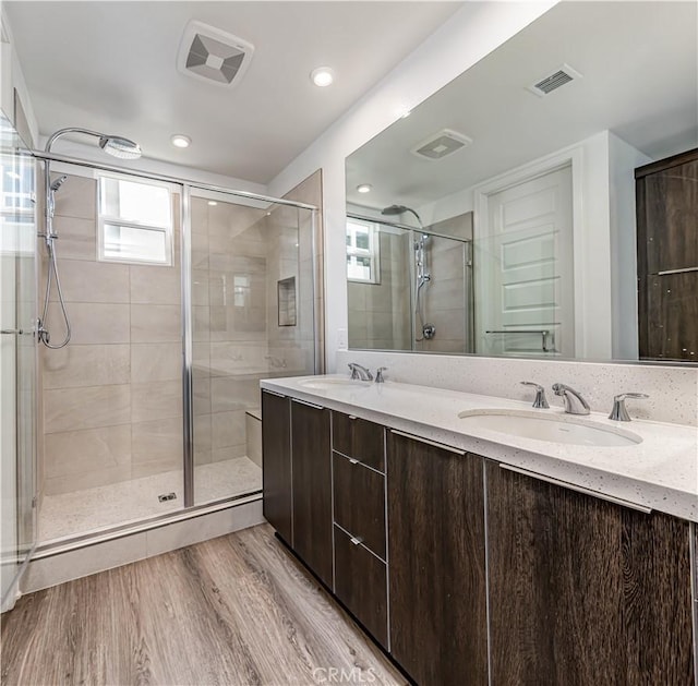 full bathroom with visible vents, a stall shower, wood finished floors, and a sink