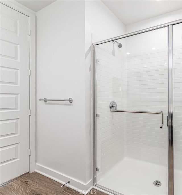 full bathroom featuring wood finished floors, a stall shower, and baseboards