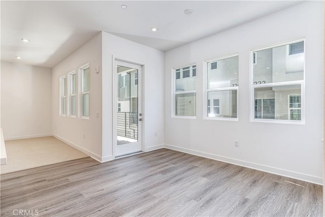 spare room with light wood finished floors, recessed lighting, and baseboards