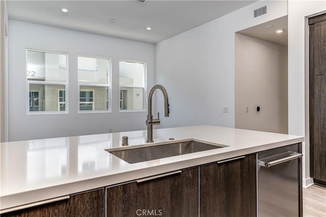 kitchen with visible vents, a sink, light countertops, dark brown cabinets, and light wood-style floors