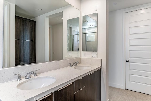 full bathroom featuring a sink, baseboards, and double vanity