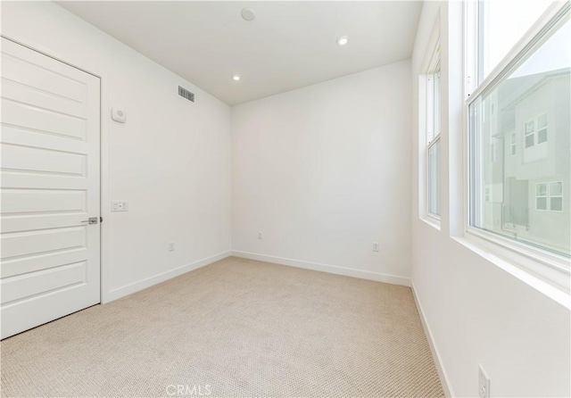 spare room with recessed lighting, light colored carpet, visible vents, and baseboards