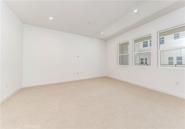 empty room featuring recessed lighting, light colored carpet, and baseboards