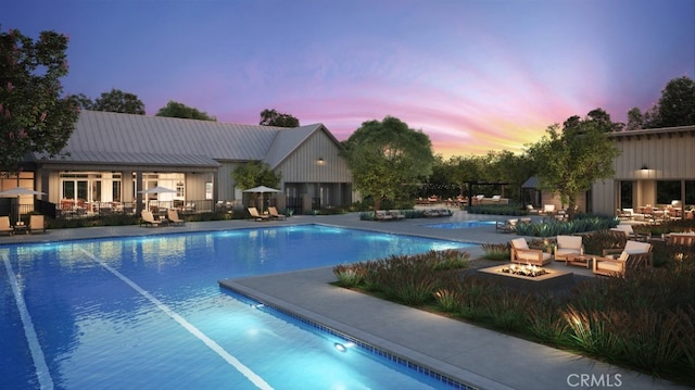 pool at dusk featuring a patio and a fire pit