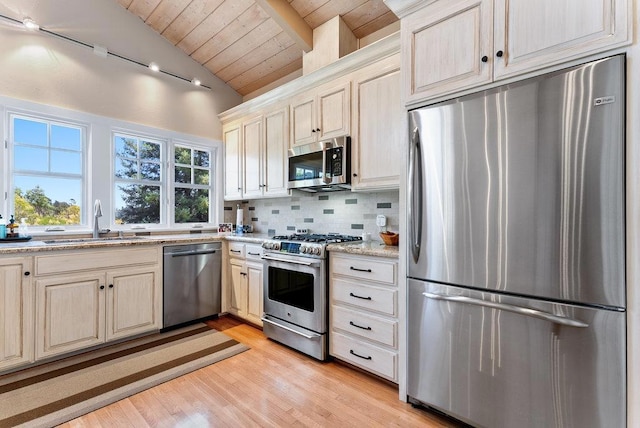 kitchen featuring sink, appliances with stainless steel finishes, tasteful backsplash, lofted ceiling with beams, and light stone countertops