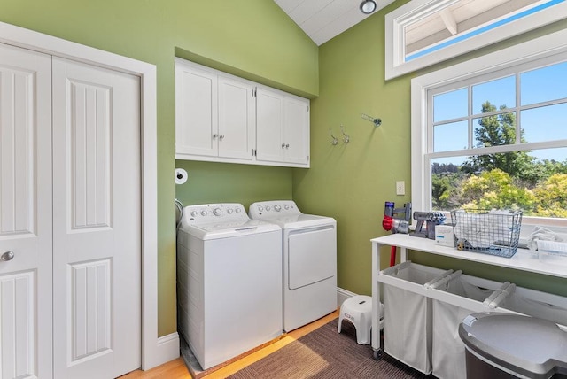 clothes washing area with hardwood / wood-style flooring, cabinets, and washer and dryer