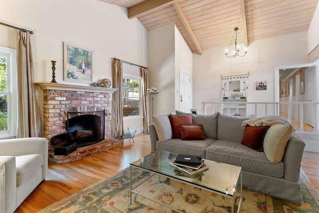 living room featuring beam ceiling, a healthy amount of sunlight, a fireplace, and light wood-type flooring