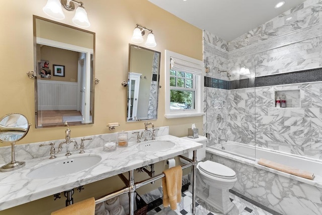 full bathroom with sink, tiled shower / bath combo, and toilet