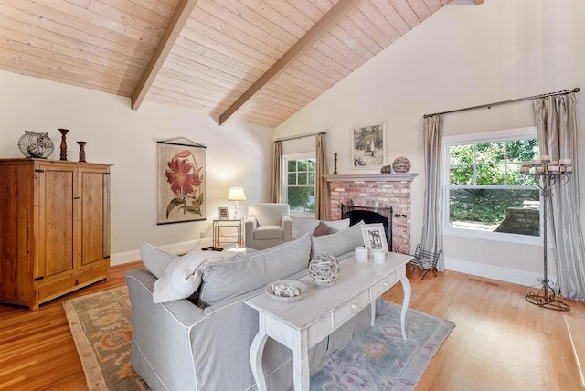 living room featuring beamed ceiling, wood ceiling, a fireplace, and light hardwood / wood-style floors