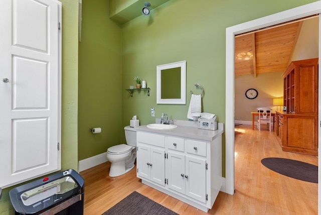 bathroom with lofted ceiling with beams, vanity, toilet, and hardwood / wood-style floors