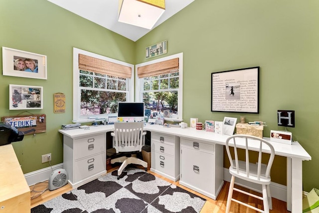 office area featuring vaulted ceiling with skylight and light hardwood / wood-style floors