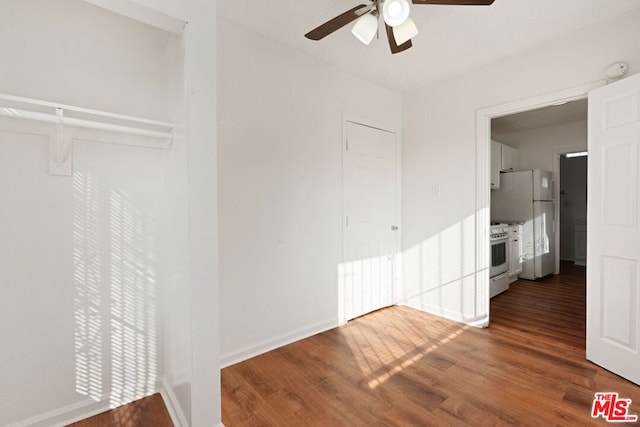 unfurnished bedroom with dark wood-type flooring, a closet, ceiling fan, and white fridge