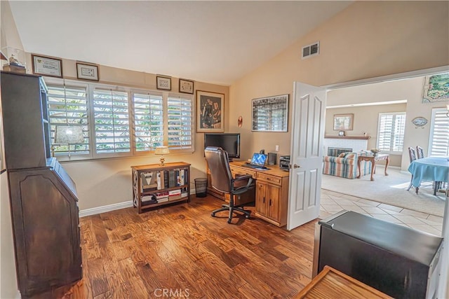 office featuring hardwood / wood-style floors, lofted ceiling, and a fireplace