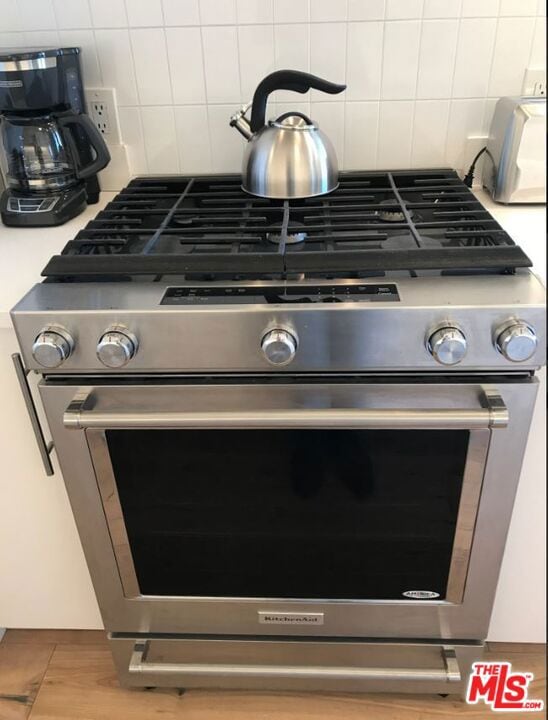 interior details featuring decorative backsplash and stainless steel gas range oven