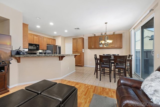 kitchen featuring pendant lighting, light hardwood / wood-style floors, stainless steel fridge, kitchen peninsula, and a breakfast bar