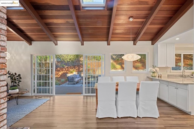 dining space featuring sink, light wood-type flooring, vaulted ceiling with skylight, and wood ceiling