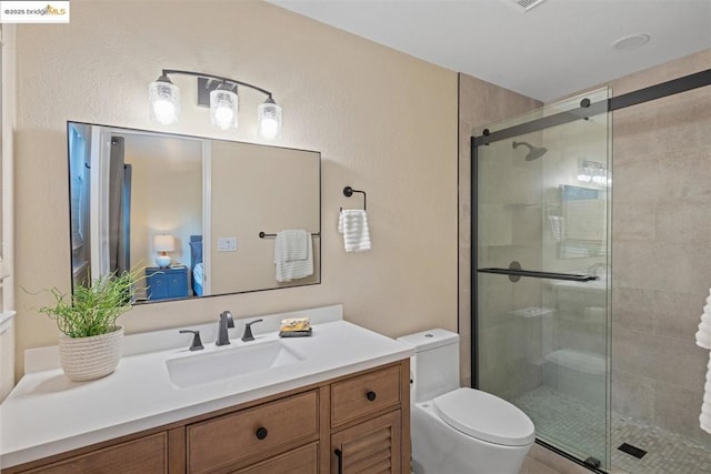 bathroom featuring toilet, a shower with shower door, and vanity