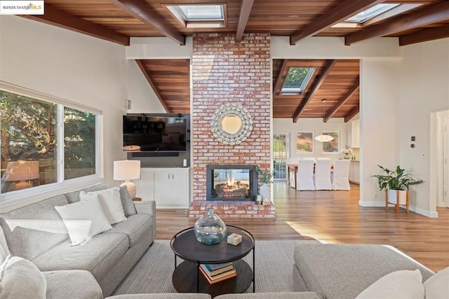 living room featuring wood ceiling, lofted ceiling with skylight, a brick fireplace, and hardwood / wood-style floors