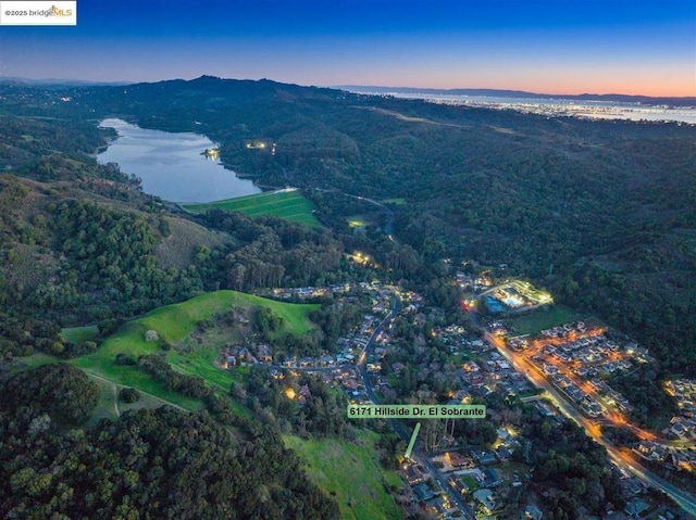 aerial view at dusk featuring a water view