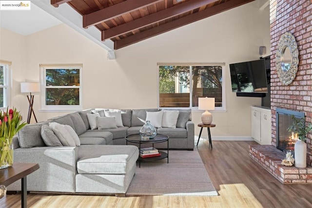 living room featuring beamed ceiling, light hardwood / wood-style floors, a fireplace, and high vaulted ceiling