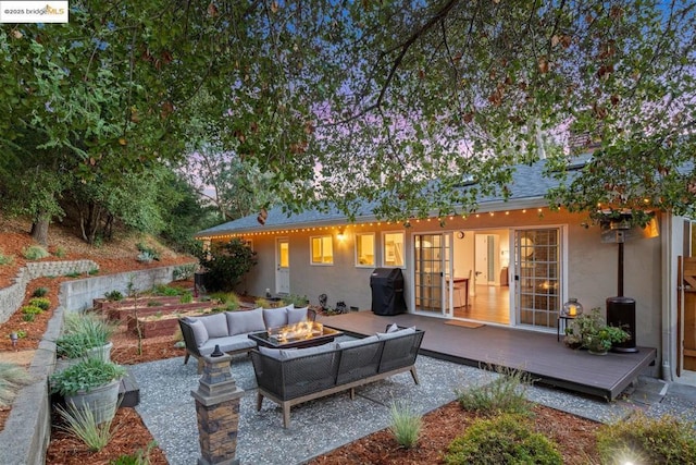 back of property with a wooden deck and an outdoor living space with a fire pit