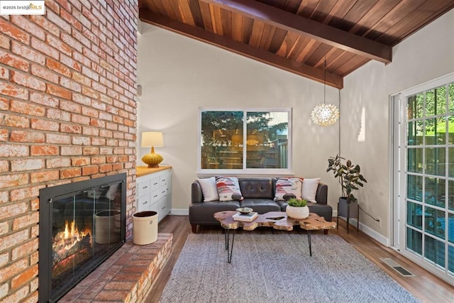 living room with a brick fireplace, vaulted ceiling with beams, and hardwood / wood-style floors