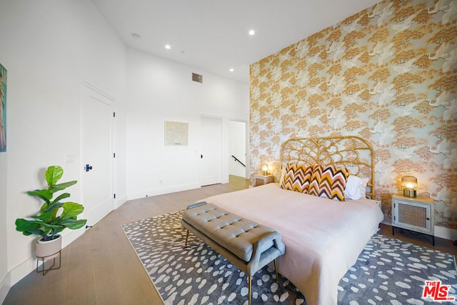 bedroom featuring a towering ceiling and dark hardwood / wood-style floors