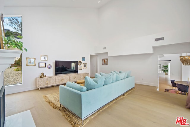 living room with a high ceiling, hardwood / wood-style floors, and an inviting chandelier