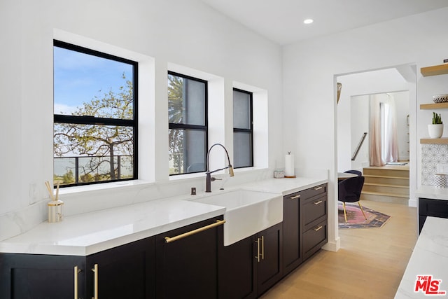 kitchen with sink, light hardwood / wood-style flooring, and light stone countertops