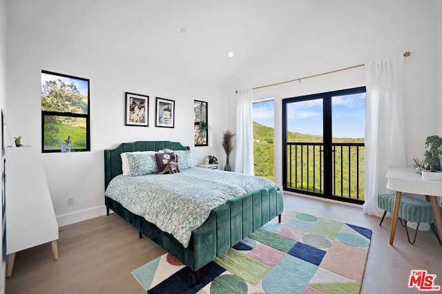 bedroom with access to exterior, high vaulted ceiling, and light wood-type flooring