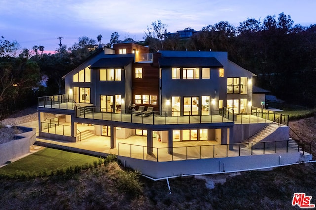 back house at dusk with a patio and a balcony