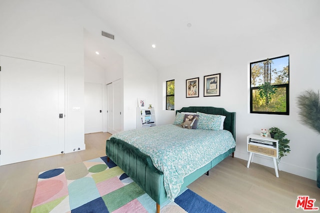 bedroom featuring high vaulted ceiling and light wood-type flooring