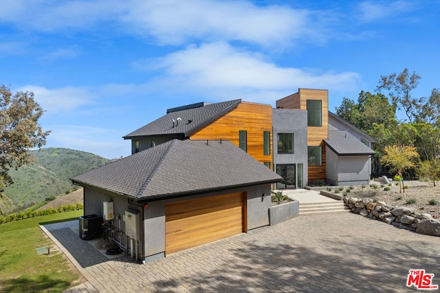 contemporary home featuring a garage, a mountain view, and central AC unit