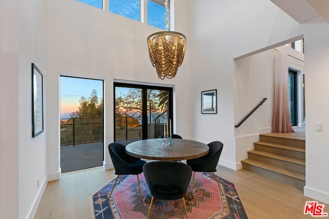 dining room with a high ceiling, an inviting chandelier, and light hardwood / wood-style floors