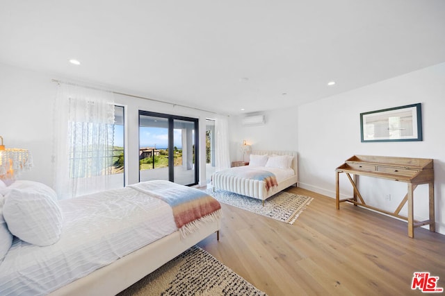 bedroom featuring french doors, access to outside, a wall unit AC, and light wood-type flooring