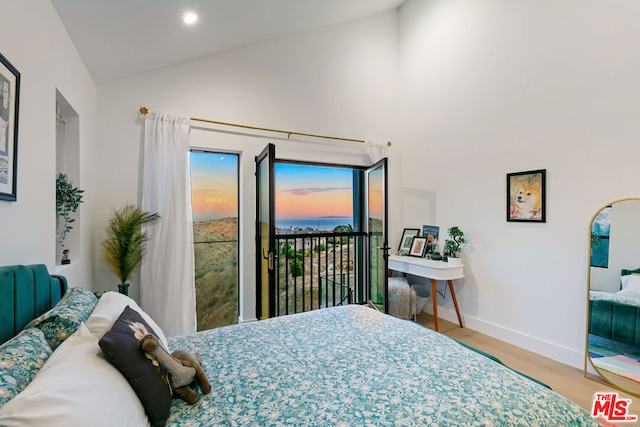 bedroom with light wood-type flooring, access to outside, and vaulted ceiling