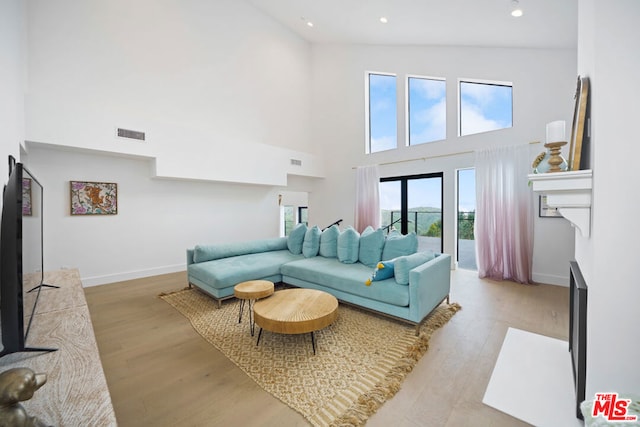 living room featuring a towering ceiling and light hardwood / wood-style floors