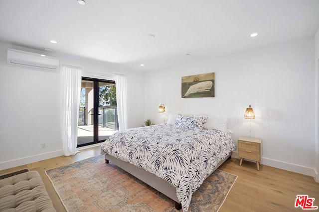 bedroom with light hardwood / wood-style floors, access to outside, and an AC wall unit