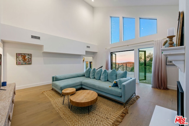 living room featuring a high ceiling and light hardwood / wood-style flooring