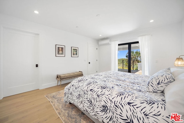 bedroom featuring access to outside, light hardwood / wood-style floors, and a wall unit AC