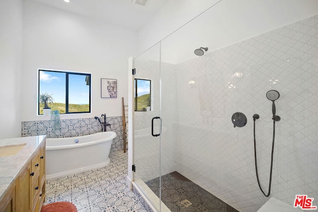 bathroom featuring tile walls, vanity, tile patterned floors, and plus walk in shower