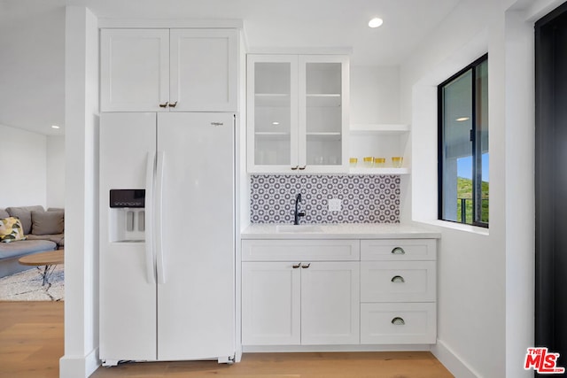 kitchen featuring white cabinetry, sink, white fridge with ice dispenser, and light wood-type flooring