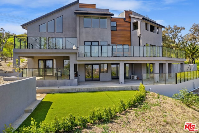 back of property featuring a balcony, a patio area, and a lawn