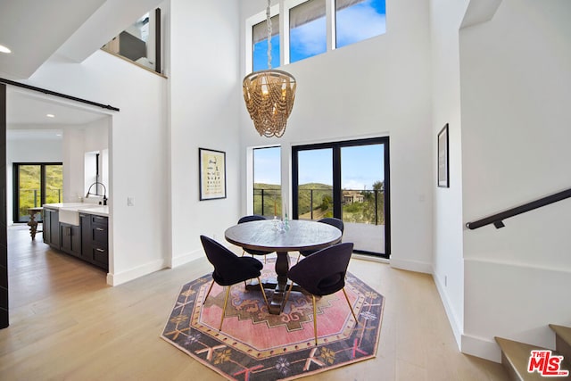 dining area featuring plenty of natural light, a chandelier, light hardwood / wood-style floors, and a high ceiling