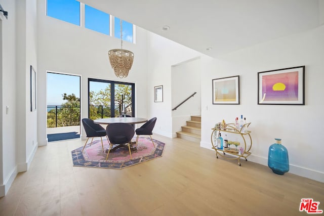 dining room featuring an inviting chandelier, a high ceiling, and light wood-type flooring