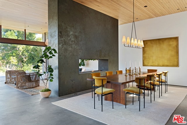 dining area featuring a high ceiling, a notable chandelier, wood ceiling, and concrete flooring