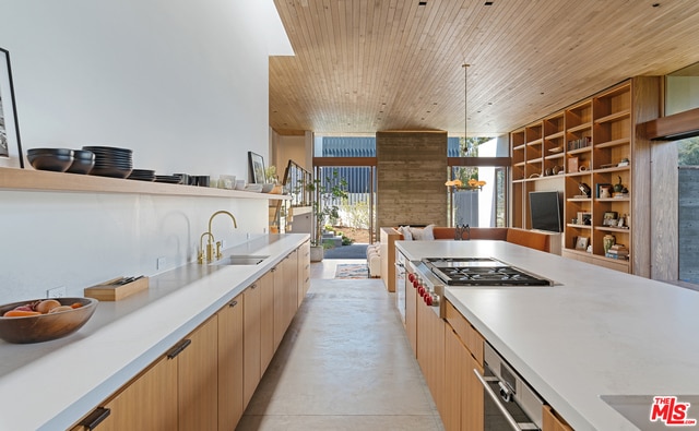 kitchen with sink, expansive windows, stainless steel gas stovetop, and wood ceiling