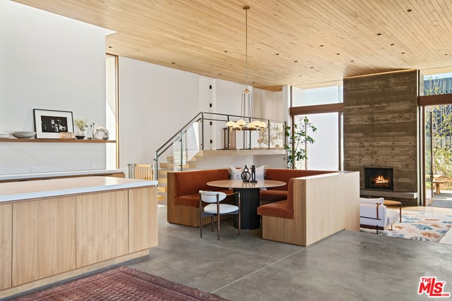 dining room with a stone fireplace, wooden ceiling, and floor to ceiling windows