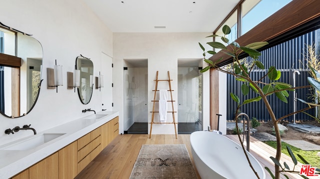 bathroom featuring hardwood / wood-style floors, vanity, and plus walk in shower